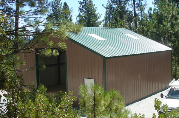A large metal barn with brown sides and green roof.